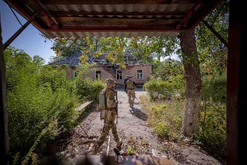 Ukraine, September 2022. Soldiers from the Ukrainian volunteer army walk in front among the ruins of the city of IzyumThe Ukrainian city of Izium (Izyum) is related  with the mass burial site discovered near by. But there are people still living there. Russia heavily bombarded the town. In  September, its forces left the area leaving behind destroyed infrastructure and a population with no food and no water and under shock.