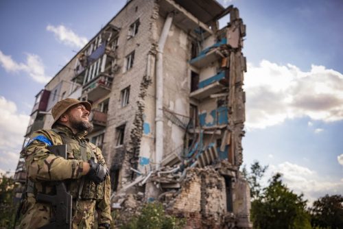 Ukraine, September 2022. Soldiers from the Ukrainian volunteer army walk in front among the ruins of the city of IzyumThe Ukrainian city of Izium (Izyum) is related  with the mass burial site discovered near by. But there are people still living there. Russia heavily bombarded the town. In  September, its forces left the area leaving behind destroyed infrastructure and a population with no food and no water and under shock.