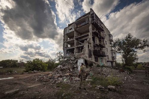 Ukraine, September 2022. Soldiers from the Ukrainian volunteer army walk in front among the ruins of the city of IzyumThe Ukrainian city of Izium (Izyum) is related  with the mass burial site discovered near by. But there are people still living there. Russia heavily bombarded the town. In  September, its forces left the area leaving behind destroyed infrastructure and a population with no food and no water and under shock.