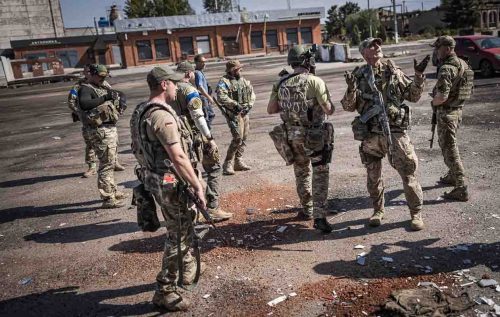 Ukraine, September 2022. Soldiers from the Ukrainian volunteer army walk in front among the ruins of the city of IzyumThe Ukrainian city of Izium (Izyum) is related  with the mass burial site discovered near by. But there are people still living there. Russia heavily bombarded the town. In  September, its forces left the area leaving behind destroyed infrastructure and a population with no food and no water and under shock.