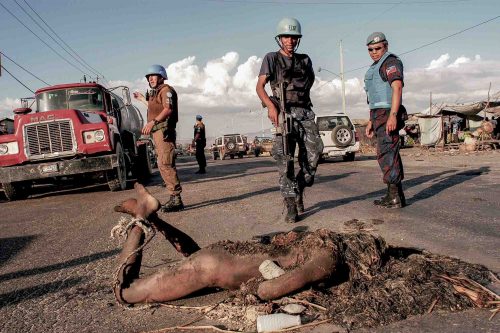 Jul 2005, Port au Prince: body of an allegated tiff. He tried to still from the market just in fron of him, someone cut his hand off and burned him Three policeman belonging to the U.N forces are standing, chilenan, philipinan and geordan.
Lorenzo Moscia/GraziaNeri